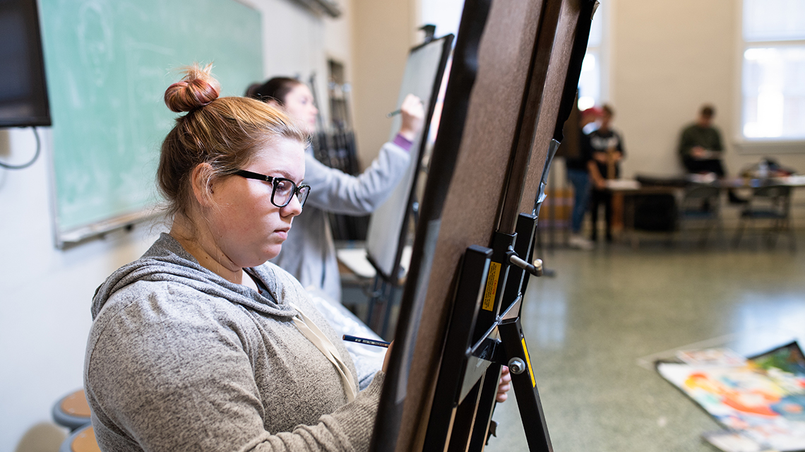 Student painting at an easel 