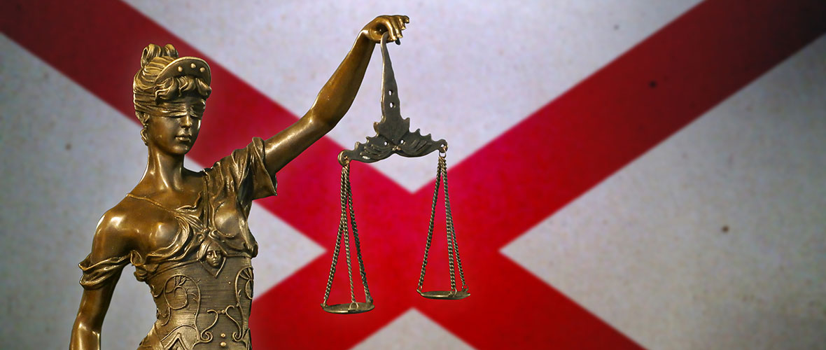 Lady Justice stands in front of the Alabama state flag.