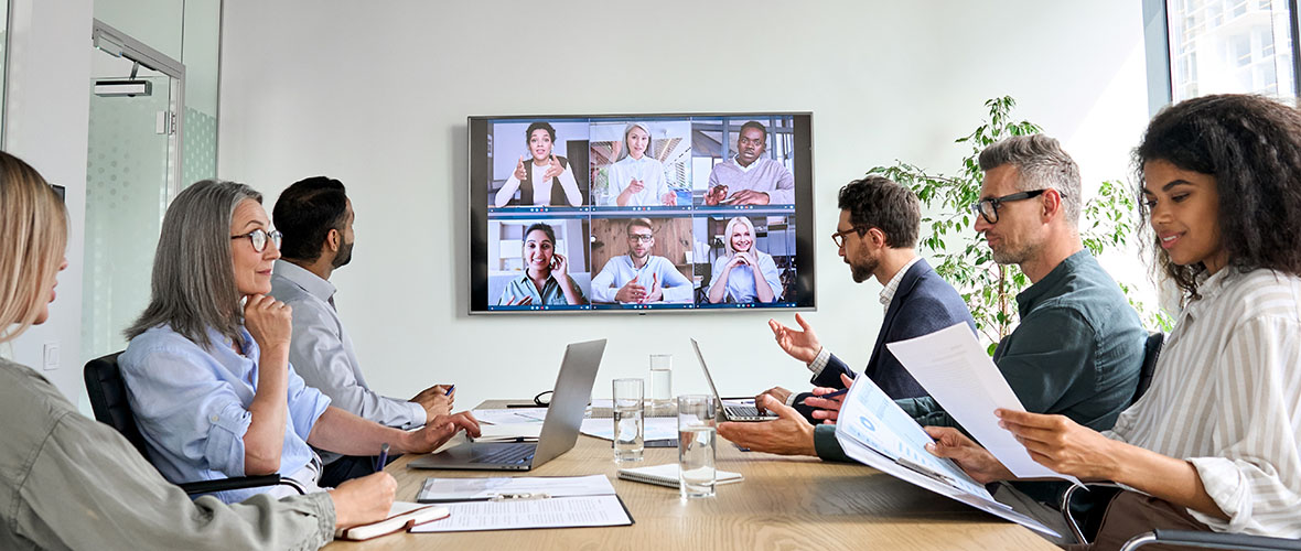 Diverse employees on online conference video call on tv screen in meeting room