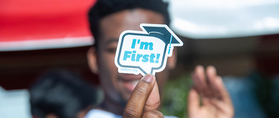 First Gen student holding sticker that says I'm first