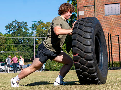 A Strong One competitor pushes a humongous tire